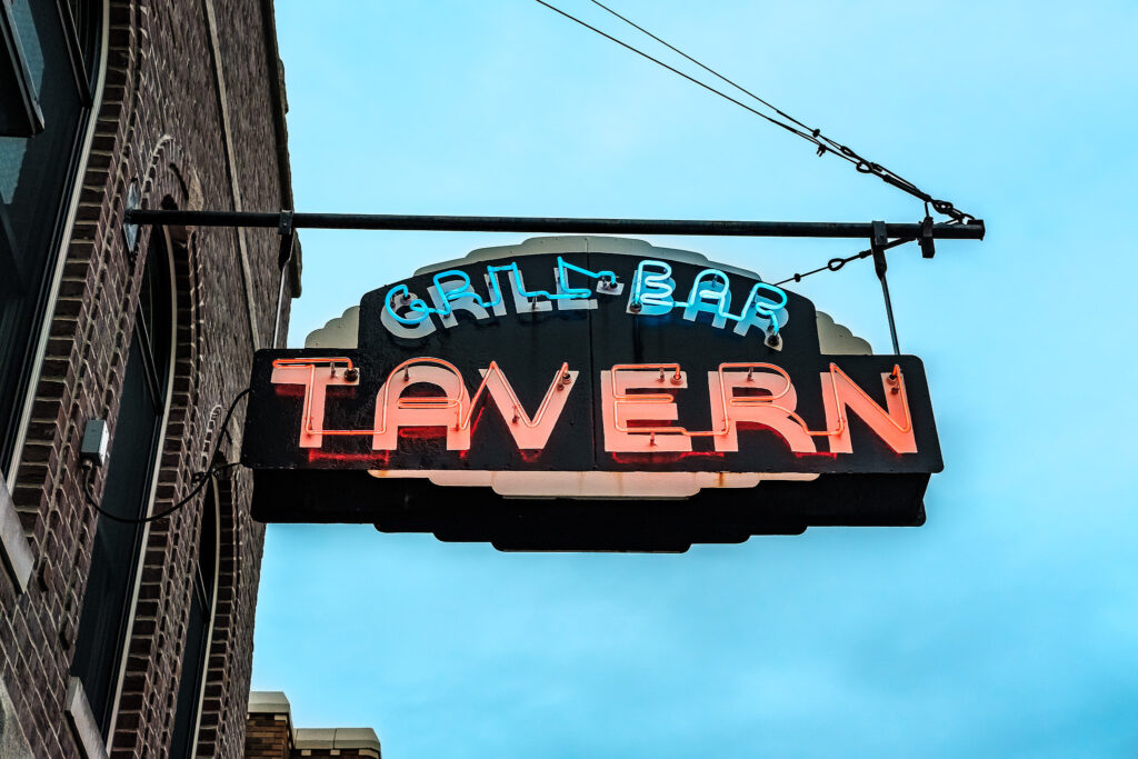 Neon sign for the Tavern Grill bar in Franklin, Indiana, hanging over the sidewalk.